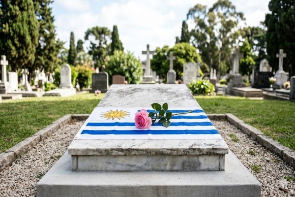 Tumba con bandera de Uruguay y rosa rosa